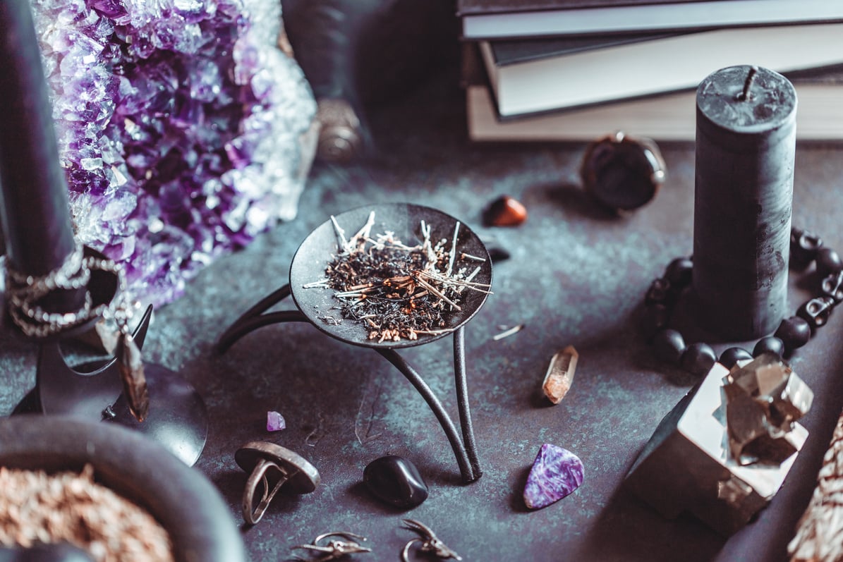 Smoked herbs on a witch's altar for a magical ritual among crystals and black candles.